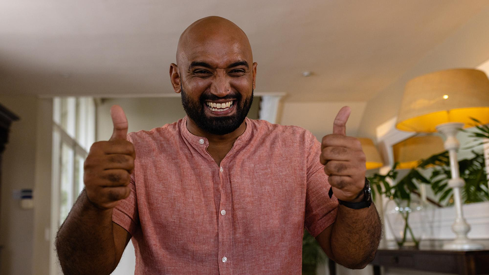man with a beard smiling widely giving two thumbs up