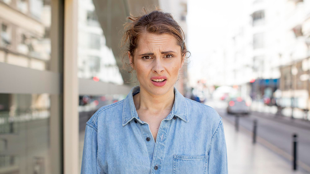 woman standing in the high street looking directly at the camer looking confused